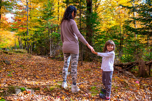 Happy mother and daughter walking along a trail in foliage season.