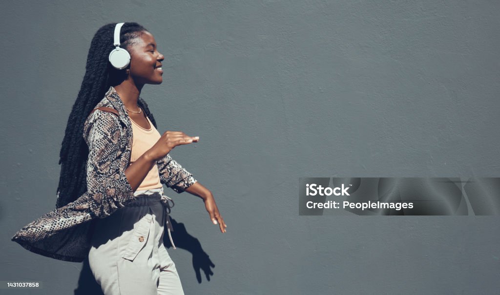 Music, university and college dance student dancing and listening to podcast or radio on headphone walking past campus. Copy space banner for education mock up content on grey wall background. Music Streaming Service Stock Photo