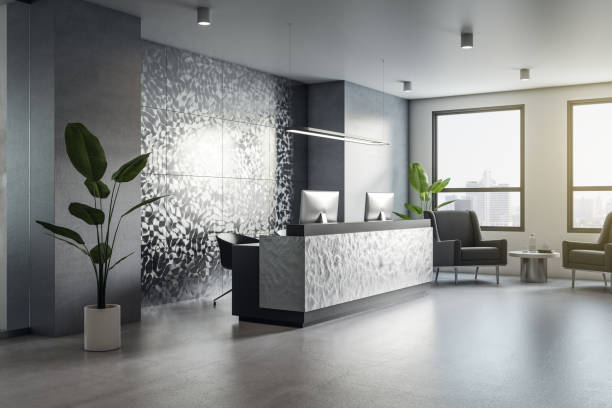istock Perspective view on stylish reception zone in spacious sunlit office with green plant on concrete floor, armchairs, city view from the windows and modern computers. 3D rendering 1431039383