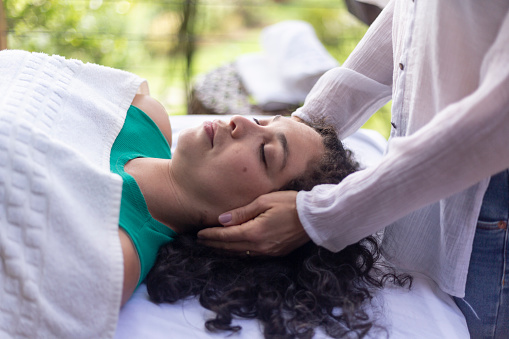 Therapist placing hands on Latina woman in reiki session