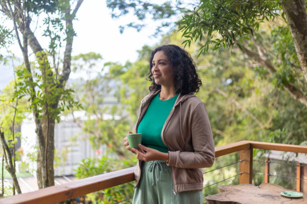 istock Latin woman drinking coffee on veranda with greenery 1431039688