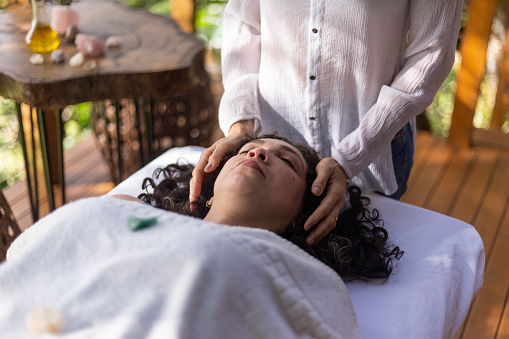 Therapist placing hands on Latina woman in reiki session