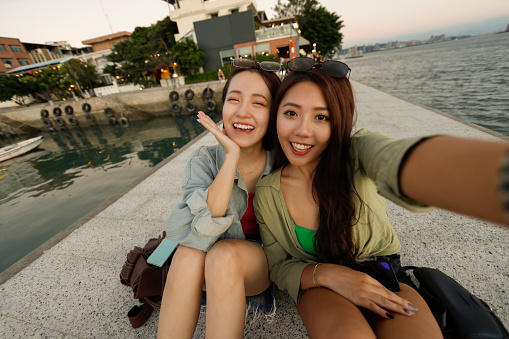 Two women travel selfie at Tamsui Pier in Taipei with sunset background