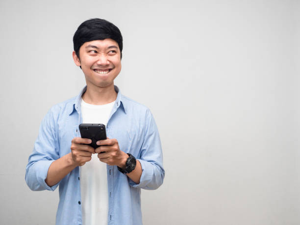 istock Positive man using mobile phone and smiling thinking about food feels hungry isolated 1431043374