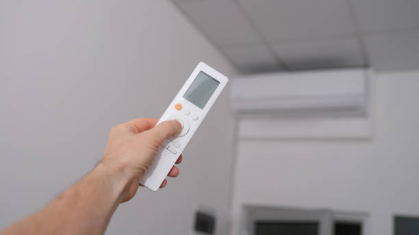 istock Hand with the remote control is directed to air conditioner 1431043701