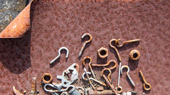 Rusted screws, nuts and bolts in a rusty iron case,
rusty nails, rusty chains, These rusty metal parts appear on the surface, rust background.