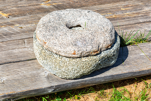 Ancient stone rotary mill for hand-grinding a grain into flour. Old hand-driven mill grinding wheat