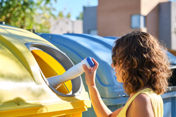 istock young woman throwing a container into the yellow recycling bin 1431046333
