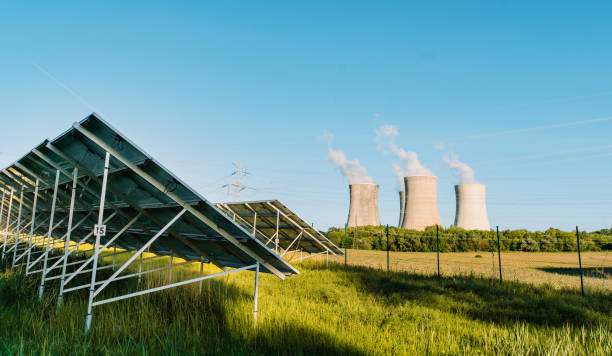 fattoria solare fotovoltaica e centrale nucleare con torri di raffreddamento sullo sfondo. ecologia - solar power station solar energy sun clean foto e immagini stock