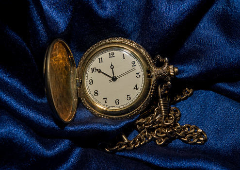 Luxury old pocket clock on blue silk fabric - vintage concept .