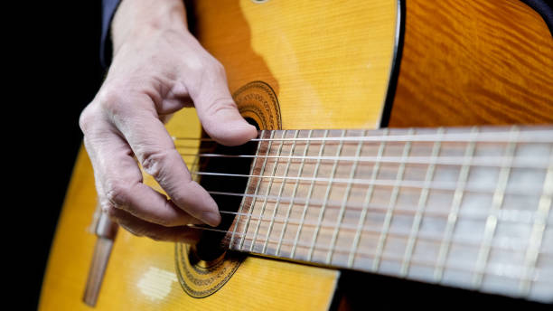 istock Guitarist playing acoustic guitar on black background, selective focus. A man playing acoustic guitar 1431053549