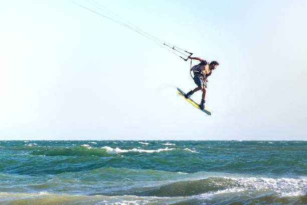 Young man kite boarder jumps over the sea at sunset. Selective focus.