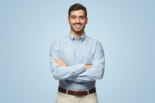 Hombre de negocios moderno con camisa azul casual de pie con los brazos cruzados sobre fondo azul photo
