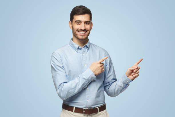 istock Smiling young business man pointing away, isolated on blue background 1431057958