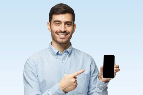 istock Man holding mobile phone in hand and pointing finger to it 1431057975