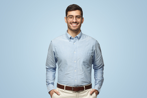 Portrait of young male teacher in blue shirt isolated on blue background