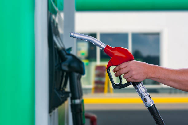 man holds a refueling gun in his hand for refueling cars. gas station with diesel and gasoline fuel close-up. - gun imagens e fotografias de stock