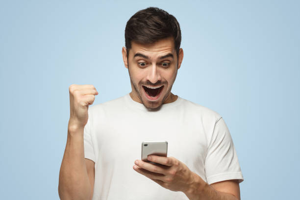 istock Happy guy holding phone having won something in Internet, perhaps in online casino 1431059301