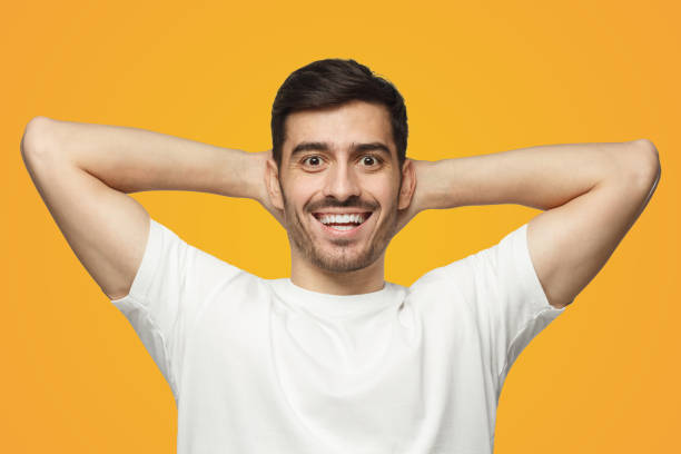 istock Young man standing isolated on yellow background with arms behind head, relaxing 1431059326