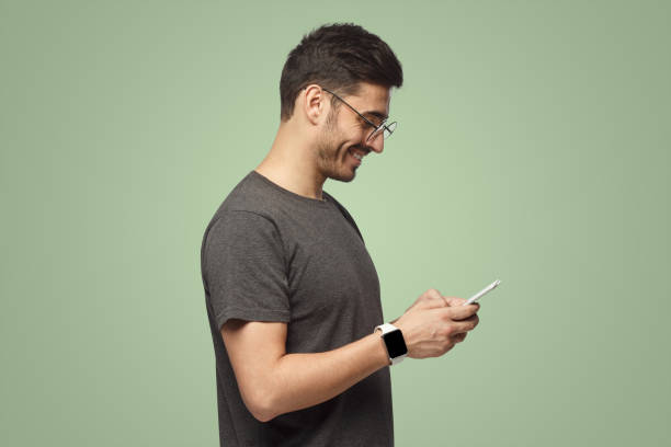 istock Side portrait of handsome man looking at screen of smartphone while exchanging messages 1431059425