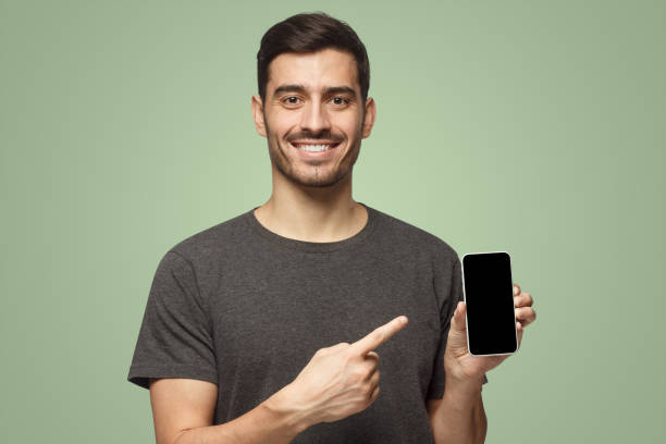 istock Happy man demonstrating blank smartphone and pointing to empty screen with smile 1431059440