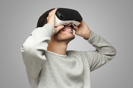 Hombre caucásico con auriculares de realidad virtual divirtiéndose mucho mientras juega photo