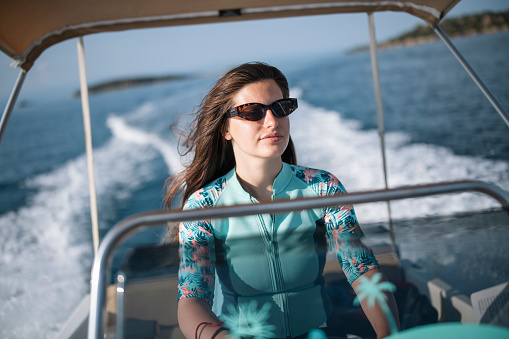 Young woman driving a boat in sea.