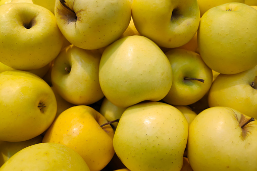 Close up on a stack of Golden Delicious apples on a market stall.