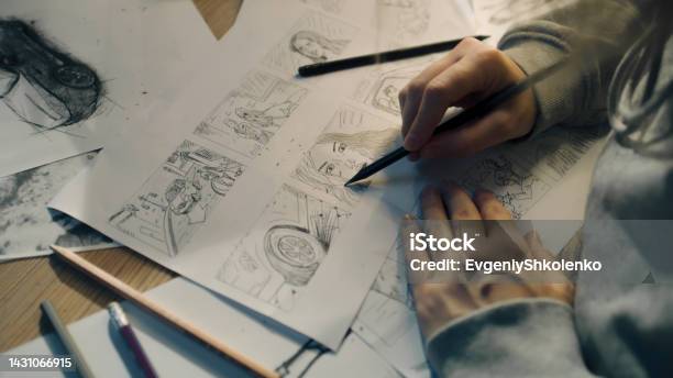 Young Female Artist Draws Sketches Of Comic Book Characters On A Sheet Of Paper Stock Photo - Download Image Now