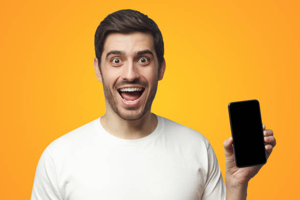 istock Excited young man holding blank phone with empty black screen, screaming WOW 1431067132