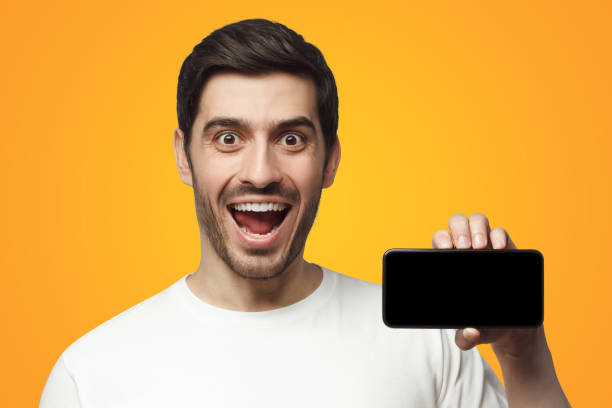 istock Young excited man showing blank screen phone in hand, isolated on yellow 1431067209