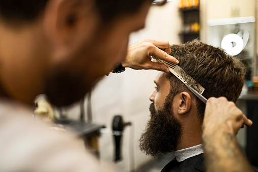 Hairdresser cutting strand of man's hair