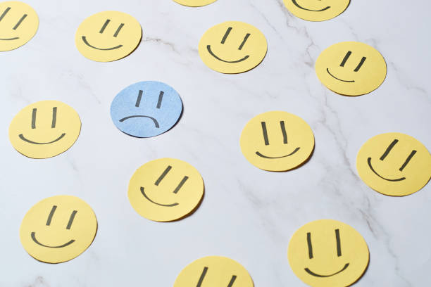 istock Sad face surrounded by happy faces. Depression and sadness disorder concept. 1431068171