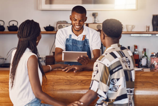 istock Hospitality, service and technology with restaurant worker  taking orders on a digital tablet, smiling and talking. Young employee manage customer payment on an online app, paying using the internet 1431068506