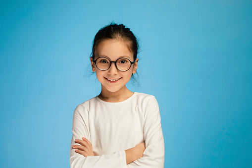 8 years old girl standing against blue background.