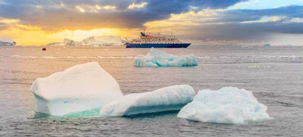 expedition ship in front of antarctic iceberg landscape in cierva cove - a deep inlet on the west side of the antarctic peninsula, surrounded by rugged mountains and dramatic glacier fronts. - ice cold glacier blue imagens e fotografias de stock