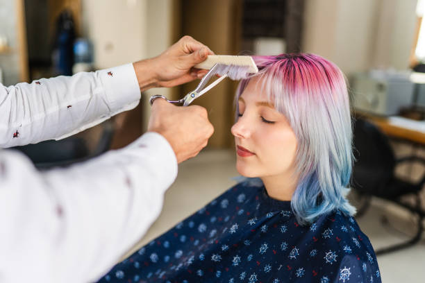 mujer joven con el pelo teñido cortándose el pelo en la peluquería - bangs fotografías e imágenes de stock