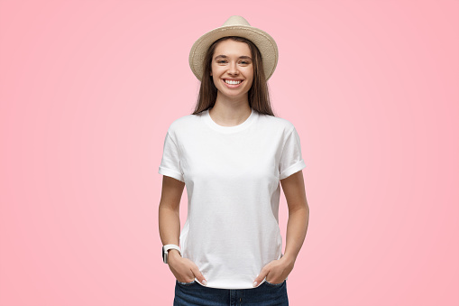 Relaxed young smiling girl in summer hat isolated on pink background