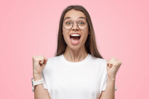istock Attractive woman shouting while her team win, raised fists in victory gesture on pink background 1431071403