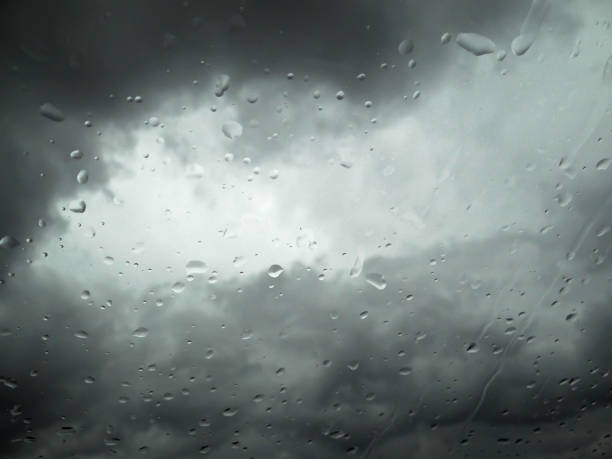 Rain drops on window with blurry dramatic sky, weather background