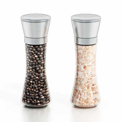 Glass and stainless steel grinders. Filled with coarse white salt grind and whole black peppercorn. Isolated on white, copy space.