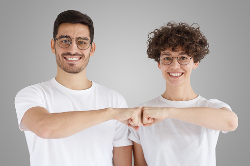Young couple celebrating with fist bump isolated on gray background