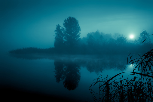 Night mystical scenery. Full moon over foggy river. Mysterious landscape.