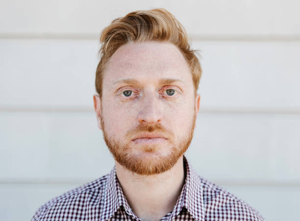 Portrait of serious redhead young adult man looking at camera outdoors stock photo