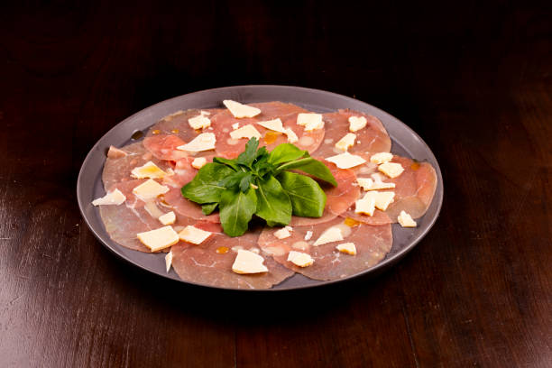 romantic dinner with carpaccio cold meats basil leaves wooden table romantic dinner with carpaccio cold meats basil leaves wooden table carpaccio parmesan cheese beef raw stock pictures, royalty-free photos & images