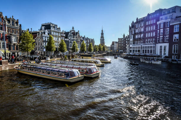 yachts amarrés sur le canal de la rivière amstel et prêts pour les touristes, pays-bas - montelbaan tower photos et images de collection