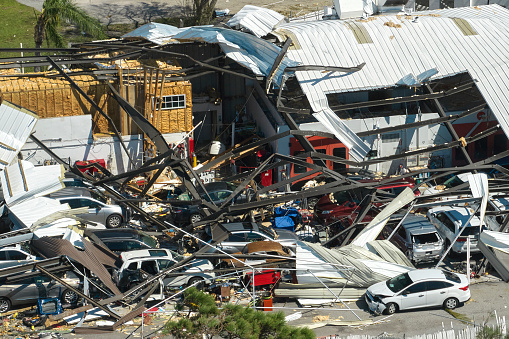 El huracán Ian destruyó un edificio industrial con autos dañados bajo ruinas en Florida. Desastres naturales y sus consecuencias photo
