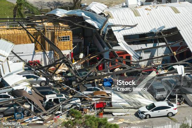 Hurricane Ian Destroyed Industrial Building With Damaged Cars Under Ruins In Florida Natural Disaster And Its Consequences Stock Photo - Download Image Now