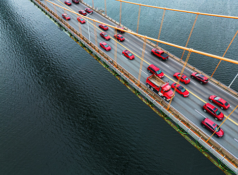 Red vehicles together on a suspension bridge at rush hour.