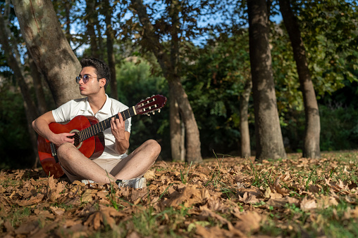 young man playing guitar in the nature
